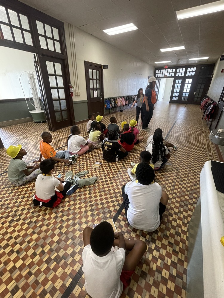 students sitting in hallway listening to instruction